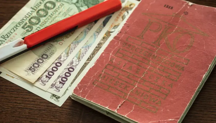 Książeczka mieszkaniowa z PRL-u, banknoty 5000 i 1000 zł oraz czerwony długopis.