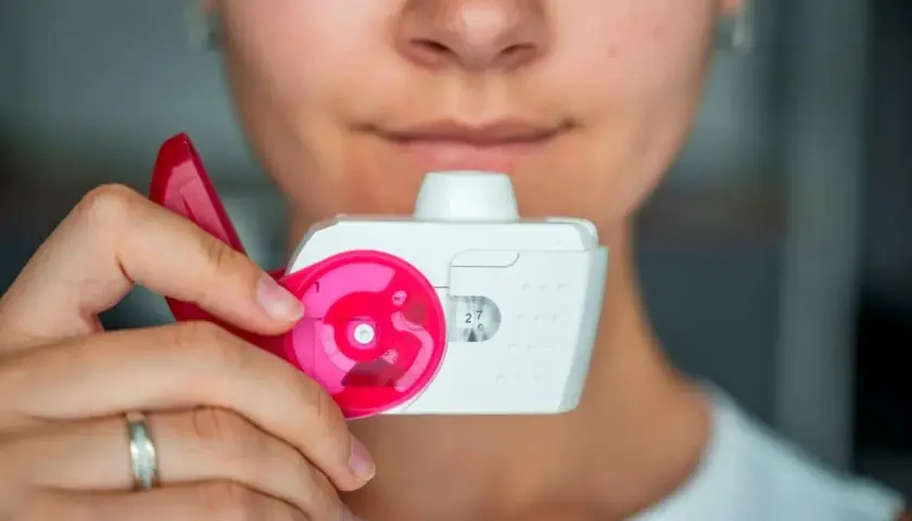 Eine Person hält einen Inhalator, bereit zum Inhalieren.
