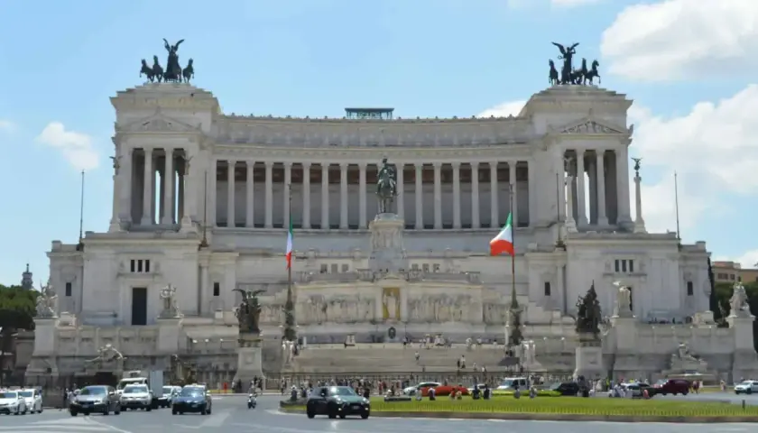 Monumentalny budynek na Piazza Venezia w Rzymie, z rzeźbami i flagami Włoch.