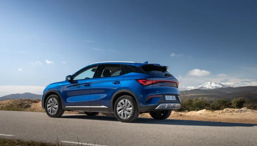 Un BYD Atto 3 azul en una carretera rural, listo para una prueba de manejo con montañas nevadas al fondo.
