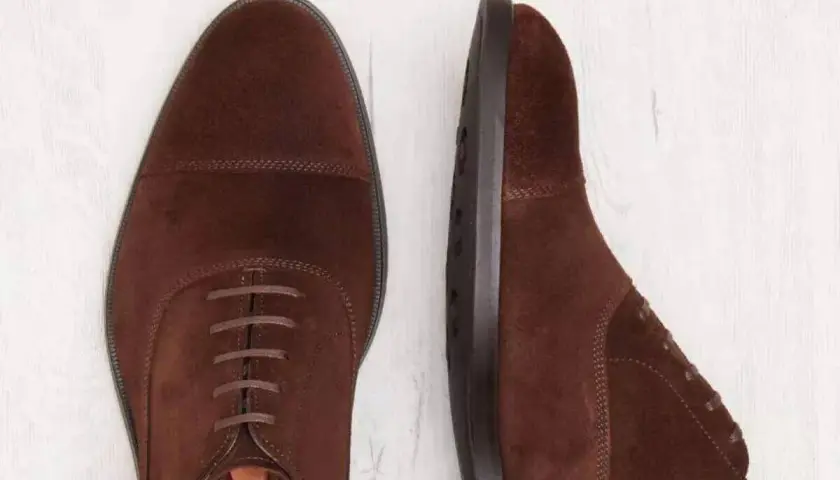 Deux chaussures richelieu en daim marron. La semelle est en cuir ou gomme, offrant confort et durabilité.