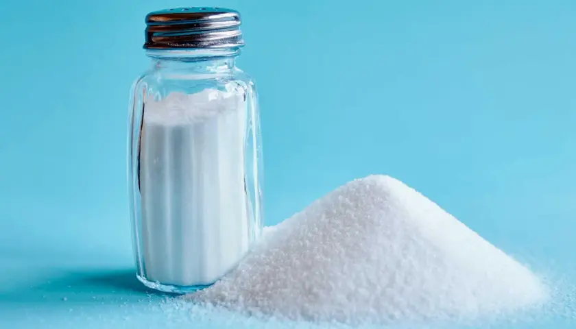 Saltkaret bredvid en hög med salt. Salt är en grundläggande ingrediens för att framhäva umami smak i matlagning.