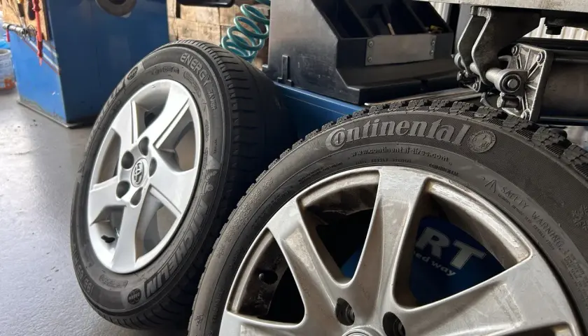 Dwa aluminiowe felgi z oponami Continental i Michelin, gotowe do prostowania felgi aluminiowej w warsztacie.