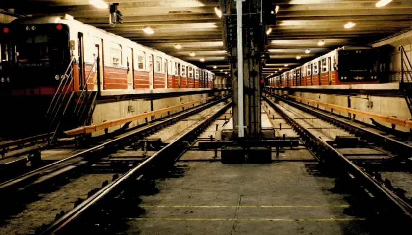 Dwa pociągi stoją na torach w podziemnej stacji metra M1.