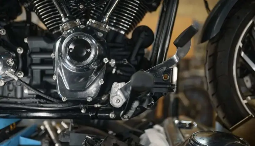 Detalle del motor de una motocicleta, mostrando el embrague y la palanca de cambios.