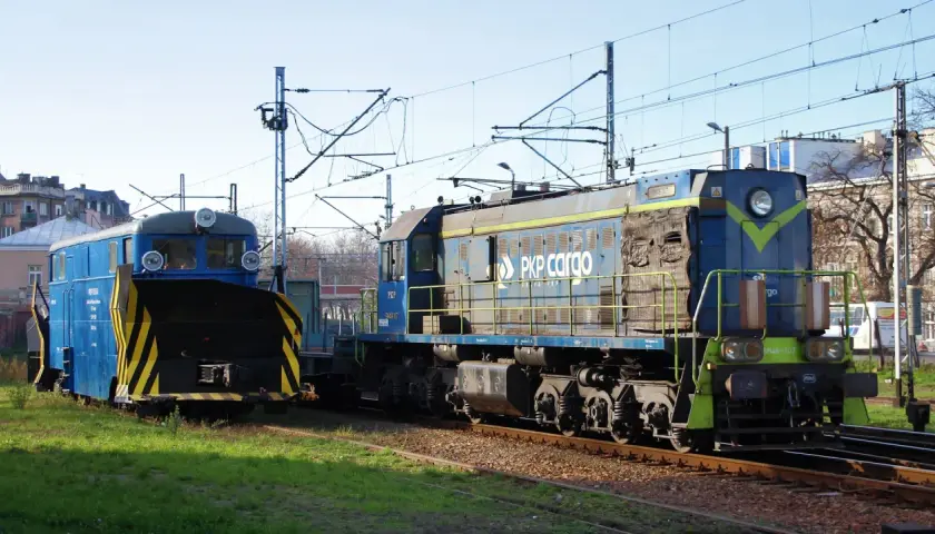 Dwie lokomotywy PKP Cargo, w tym jedna z pługiem śnieżnym, stoją na torach. Lokomotywa tem2 jest niebieska z żółtymi pasami.