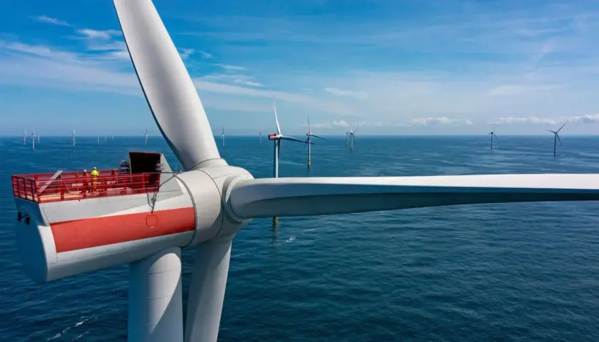 Wielka turbina wiatrowa na morzu, część projektu Baltica 2, z pracownikami na platformie. W tle widać kolejne morskie farmy wiatrowe.