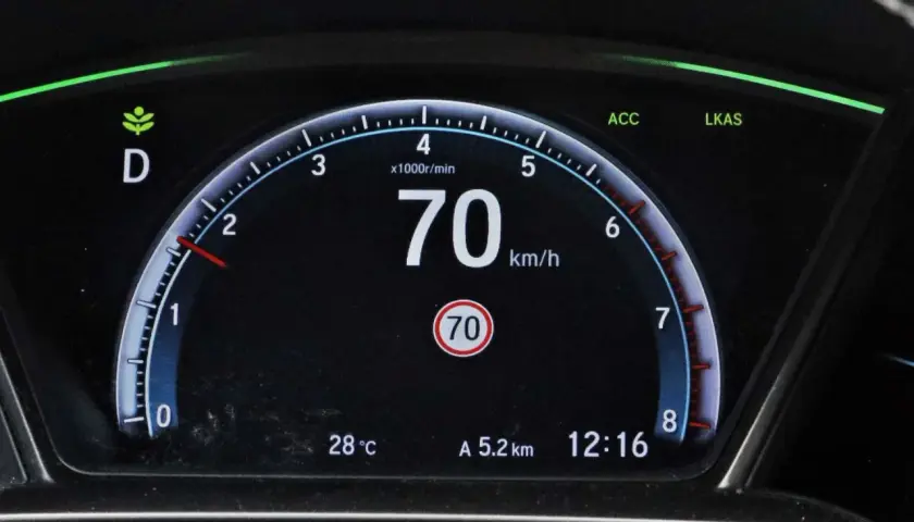 Cyfrowy prędkościomierz samochodu pokazuje 70 km/h, obok wskaźnik temperatury i zegar.