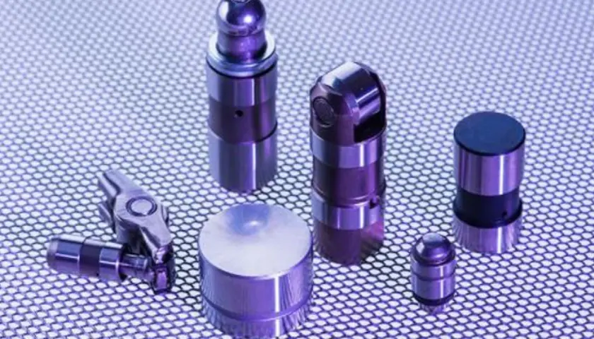 Varios taques hidráulicos de metal, algunos con forma cilíndrica y otros con un diseño más complejo, dispuestos sobre una superficie texturizada.