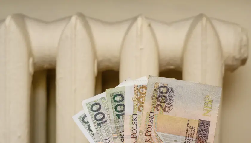 Pieniądze w ręku na tle grzejnika. Czy to zapowiedź bonu energetycznego 2026?