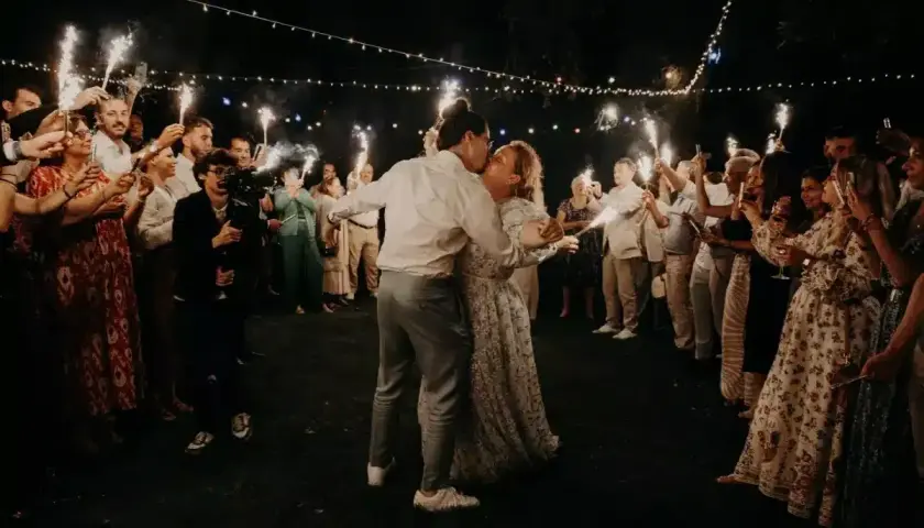 Mariage intime pour 30 personnes : le couple s'embrasse sous les feux de la rampe, entouré de ses proches.