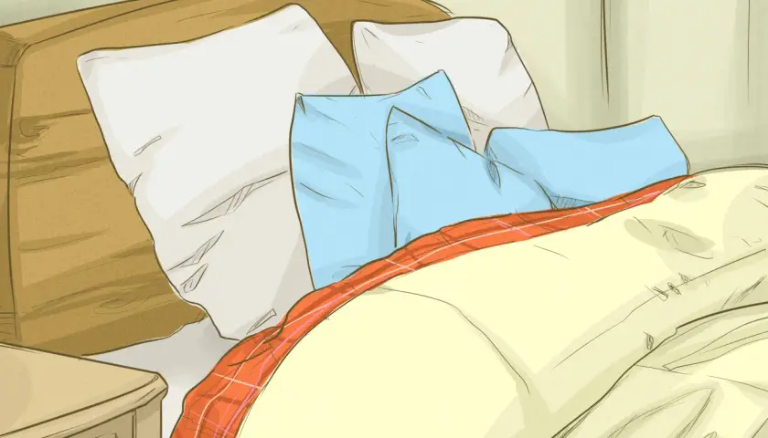 Cozy bed with pillows and a plaid blanket, perfect for learning how to get warmer in bed.