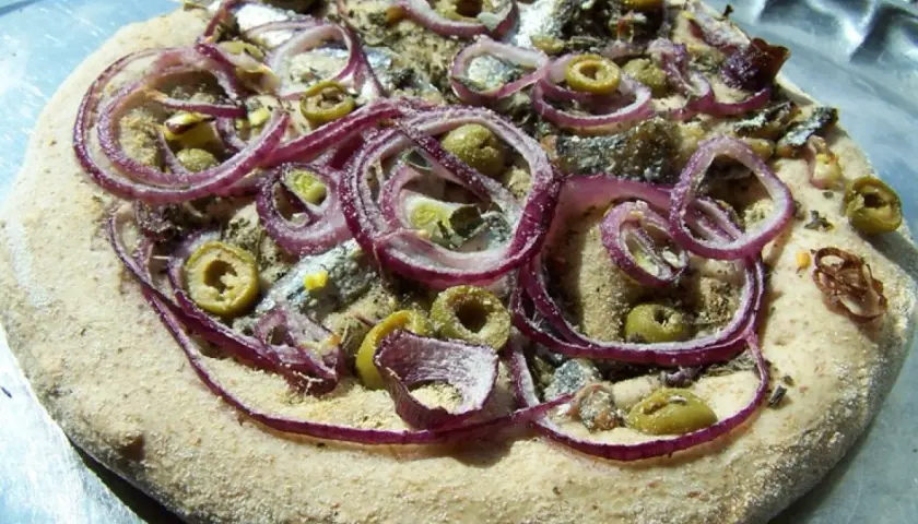 Pizza z anchois, oliwkami i czerwoną cebulą na chrupiącym cieście.