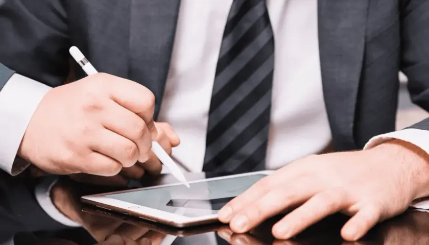 Hombre con traje firma un contrato con certificado digital en una tablet.