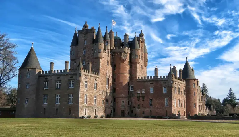 Castillo escocés con torres cónicas y un gran césped verde, perfecto para tus viajes a Escocia.