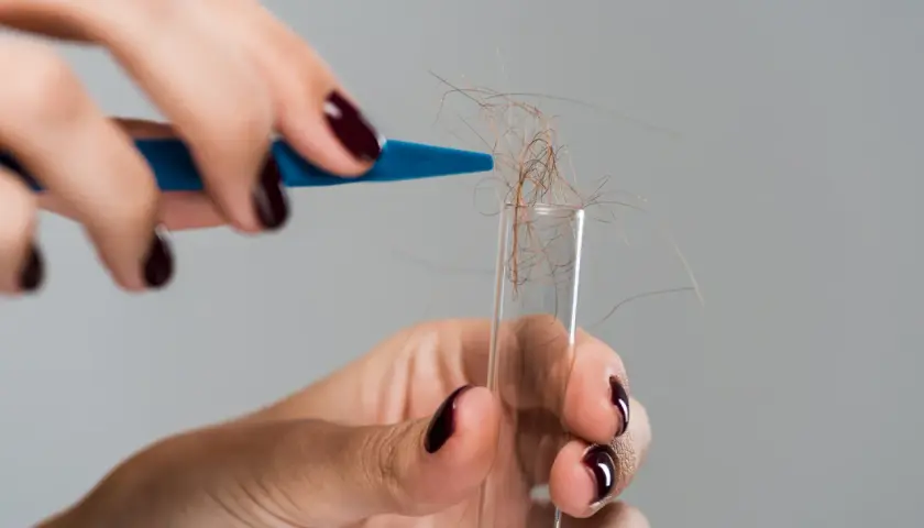 Hårstrån samlas i ett provrör, kanske för ett allergi test.