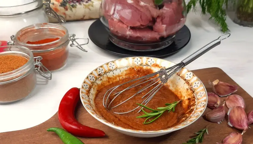 Przygotowanie marynaty do polędwiczki wieprzowej: miska z przyprawami, chili, czosnek i mięso w tle.