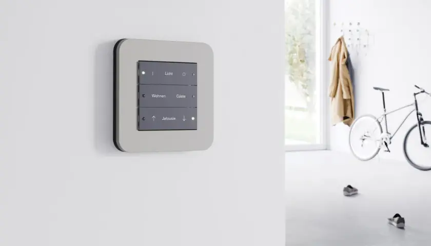 Panel de control moderno con botones para luz, salón y persianas, parte de dispositivos KNX para automatización del hogar.
