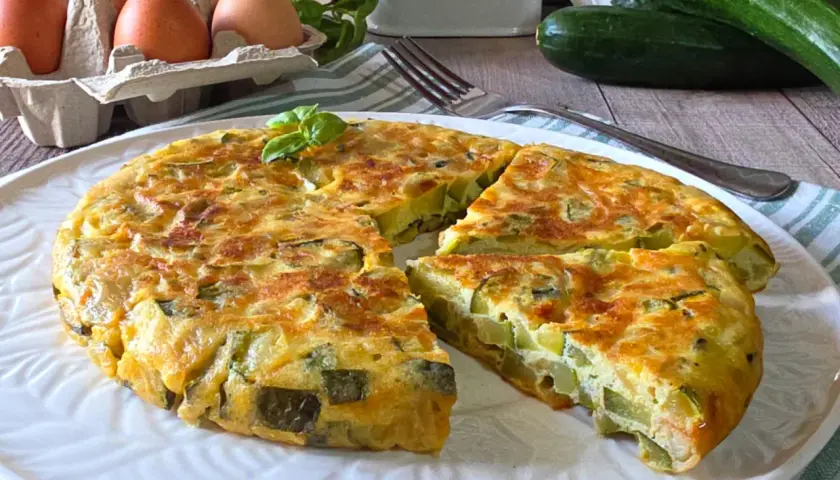 Una gustosa frittata di zucchine, dorata e soffice, con ingredienti freschi come uova e basilico.