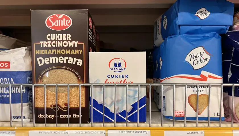Półka sklepowa z różnymi rodzajami cukru: trzcinowym, białym w kostkach i w kryształkach.