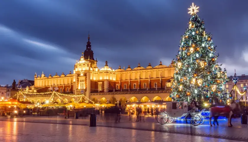 Magiczny jarmark bożonarodzeniowy krakow. Rozświetlona choinka, Sukiennice i karoca z końmi tworzą świąteczną atmosferę.
