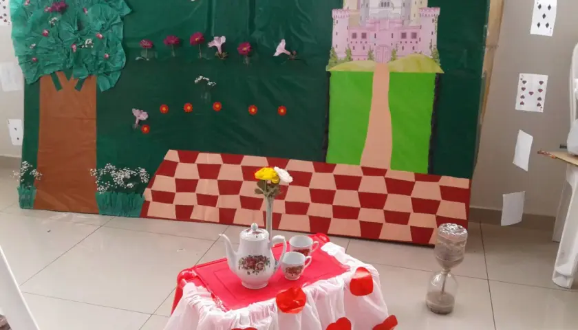 Escenario de manualidades alicia en el país de las maravillas con castillo, árbol, mesa de té y reloj de arena.