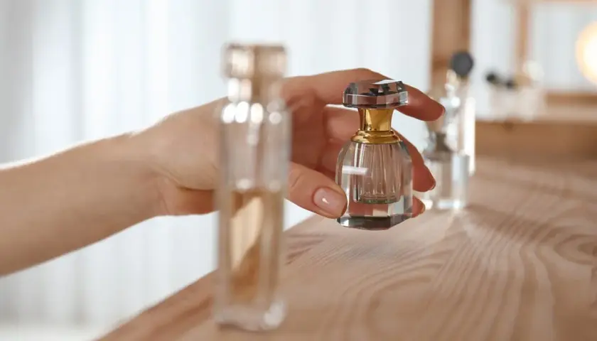 Dłoń trzyma małą, kryształową buteleczkę perfum. Proces maceracji perfum wymaga cierpliwości.