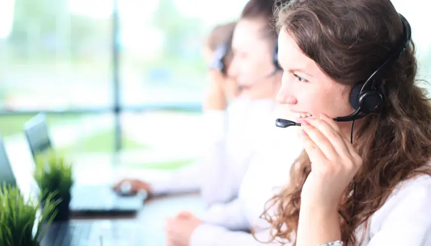 Callcenter-Mitarbeiterin mit Headset, die lächelt. Kundenservice ist ihr mos wert.