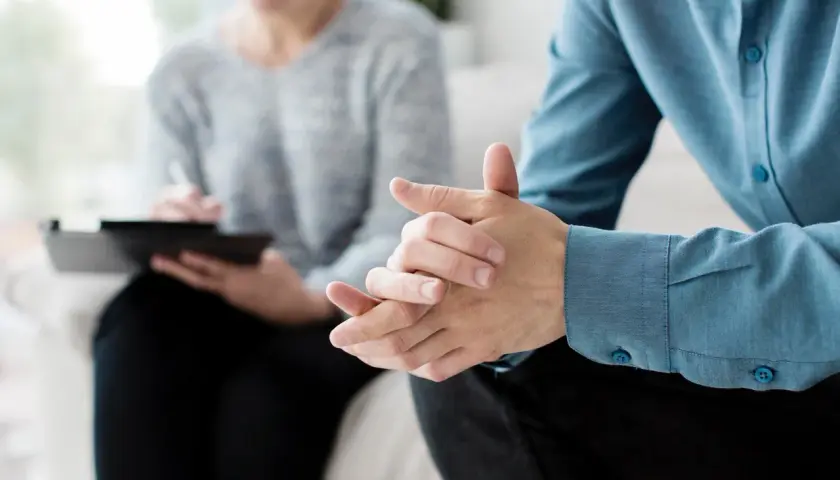 Due mani intrecciate in un colloquio, forse per affrontare la ruminazione mentale e valutare l'uso di farmaci.