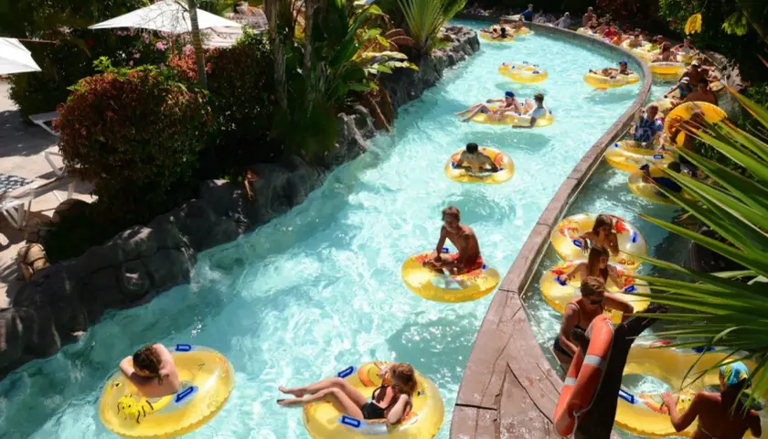 Un día perfecto de diversión en Tenerife con niños, flotando en un río artificial rodeado de vegetación exuberante.