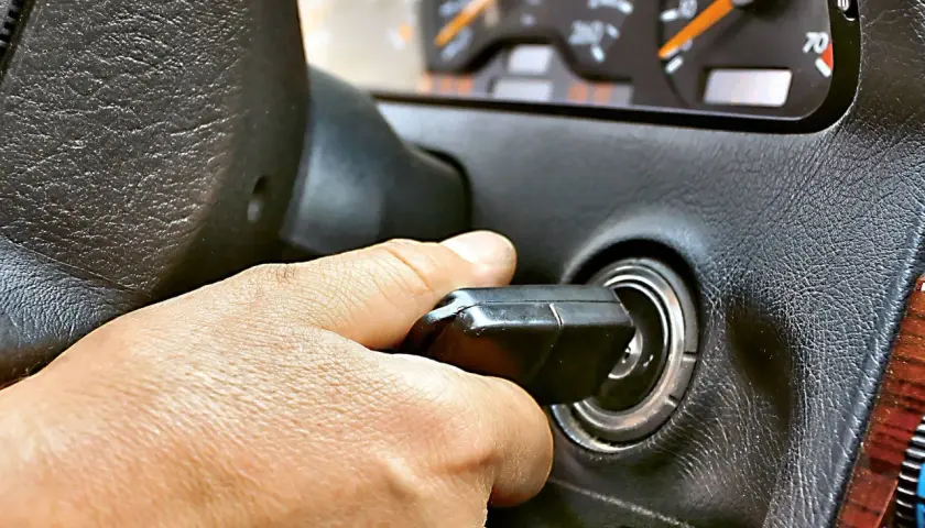Dłoń przekręca kluczyk w stacyjce. Auto odpala i gaśnie, co sugeruje problem z zapłonem lub paliwem.