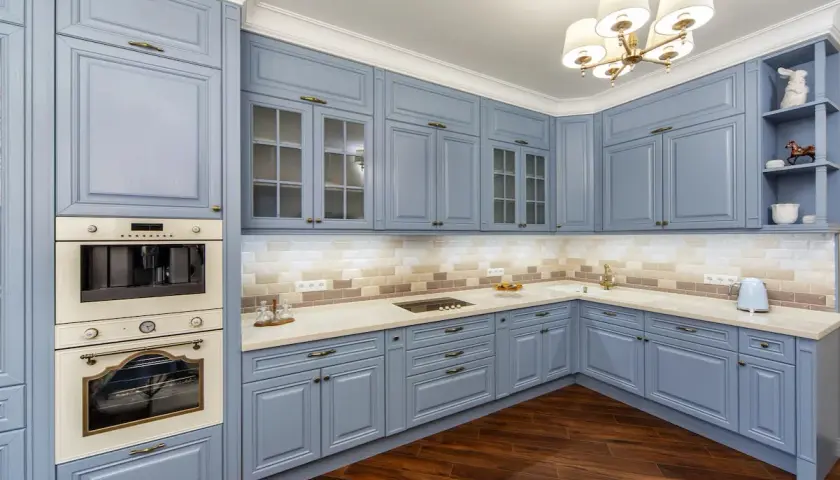 Cucina moderna con mobili blu polvere, un'idea per cambiare colore alla cucina. Pavimento in legno scuro e illuminazione soffusa.