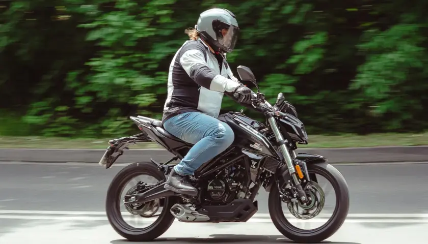 Mężczyzna w kasku jedzie czarnym motocyklem. Idealny motor na kat B, by poczuć wolność na drodze.