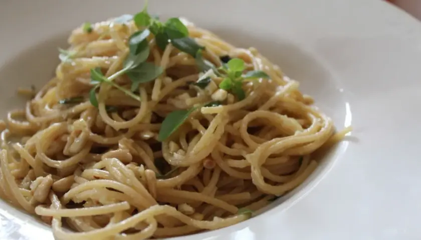 Deliciosa pasta con piñones y hierbas frescas, servida en un plato blanco.