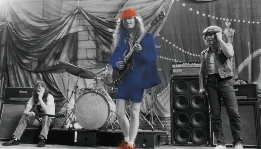 AC/DC na scenie, grający swoje największe przeboje. Angus Young w czerwonej czapce i Angusem Youngiem na scenie, grający swoje największe przeboje.