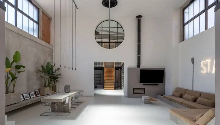 Geräumiger **Industrie-Loft** mit Betonwänden, großem Esstisch, Kamin und gemütlicher Sitzecke.
