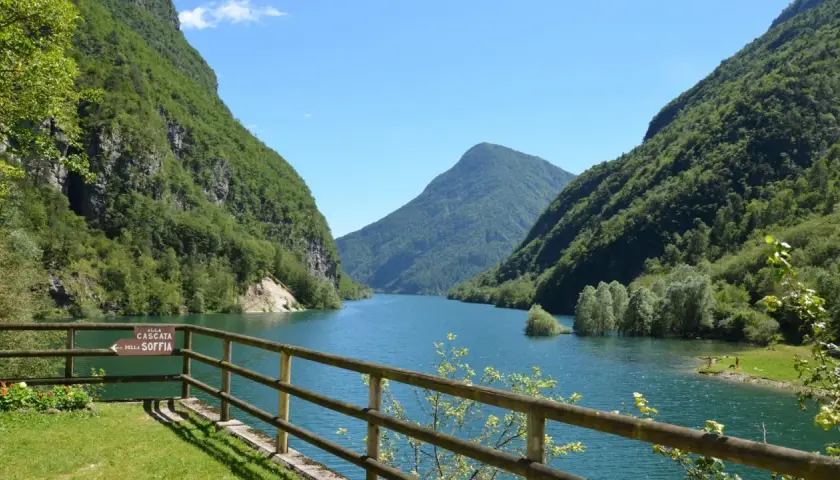 Il lago del Mis, incastonato tra montagne verdi e rigogliose, offre uno spettacolo mozzafiato con le sue acque azzurre e il cielo limpido.