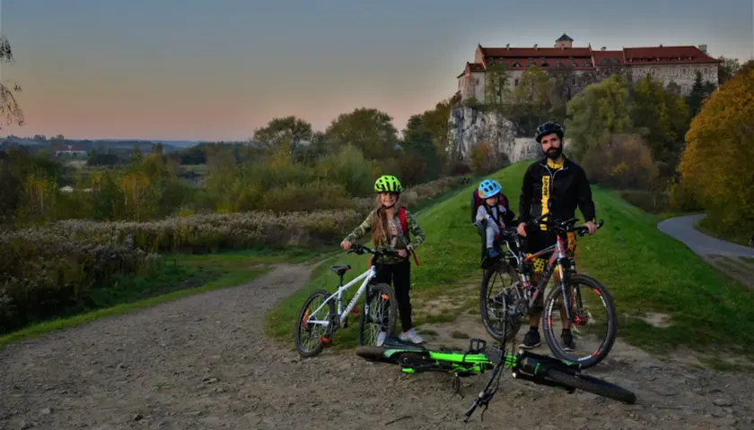Rodzina na rowerach pod zamkiem, odkrywają malownicze trasy rowerowe Małopolska.