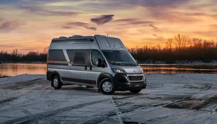 Srebrny kamper Globe-Traveller na tle zachodzącego słońca nad rzeką. Idealny, jaki kamper dla 2 osób na zimową podróż.