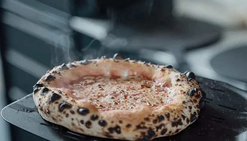 Frisch gebackene Pizza mit dampfendem Käse auf einem Pizzaschieber. Eine von vielen köstlichen Pizza sorten, bereit zum Servieren.
