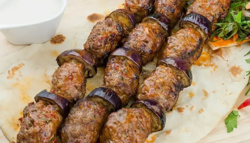Grillowane szaszłyki z mielonego mięsa i bakłażana, czyli pyszna kofta libańska, podane na chlebku z sosem.