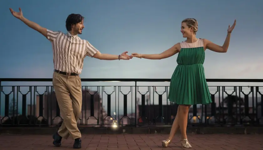 Coppia balla con gioia, un uomo e una donna in abiti retrò, mostrando cos'è lo swing con movimenti aggraziati al tramonto.