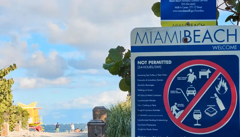 Miami Floryda Stany Zjednoczone: tablica z zakazami na plaży, w tle ocean i ratownicza wieża.