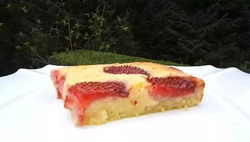 Un délicieux clafoutis aux fraises, tout juste sorti du four, sur une assiette blanche.
