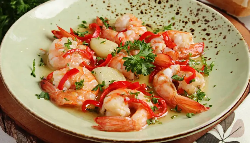 Garnelen in Knoblauchöl mit Paprika und Petersilie, ein köstliches Gericht, das perfekt zu einem Glas Wein passt.