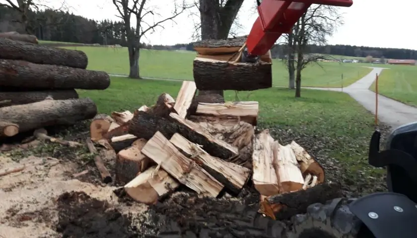 Bagger mit Kegelspalter spaltet Holz. Gebraucht, aber leistungsstark für Brennholz.