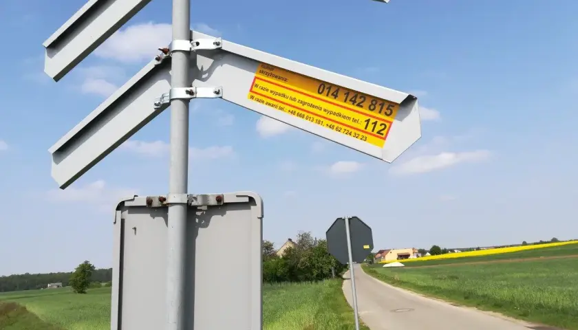 Znak informuje o numerze skrzyżowania i numerach alarmowych w razie wypadku lub awarii na przejeździe kolejowym.