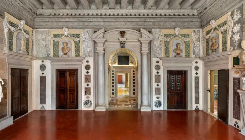 Intérieur du Palazzo Grimani, avec ses portes en bois sombres, ses bustes en marbre et ses décorations murales élaborées.