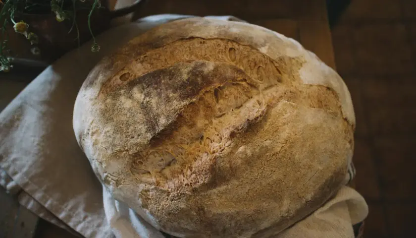 Świeżo upieczony, okrągły bochenek chleba na lnianej ściereczce.