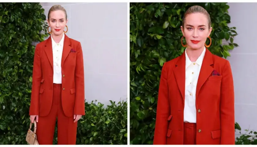 Elegancki komplet czerwony damski Emily Blunt. Aktorka prezentuje się stylowo w garniturze i białej koszuli, z torebką i okrągłymi kolczykami.